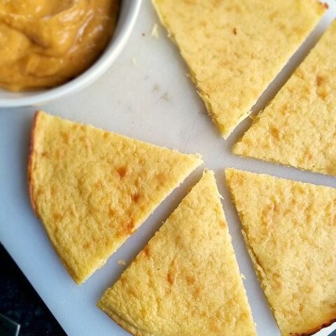 Socca cut into wedges on white cutting board