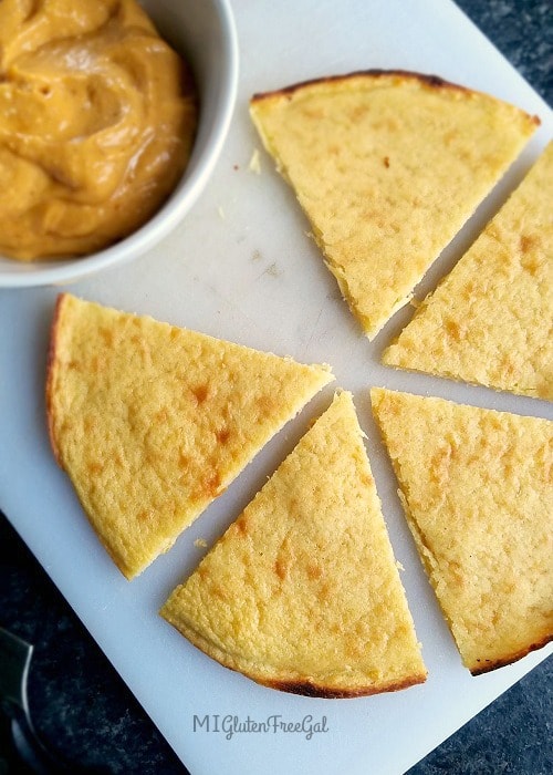 Socca cut into wedges on white cutting board